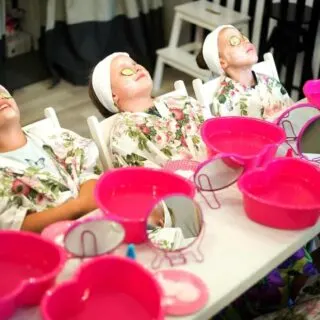 Little girls sit in a row and get facials as part of a spa party for little girls