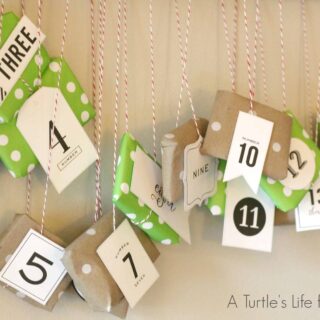 A DIY advent calendar made from kraft paper and scrapbook paper hanging on a wall from a pole