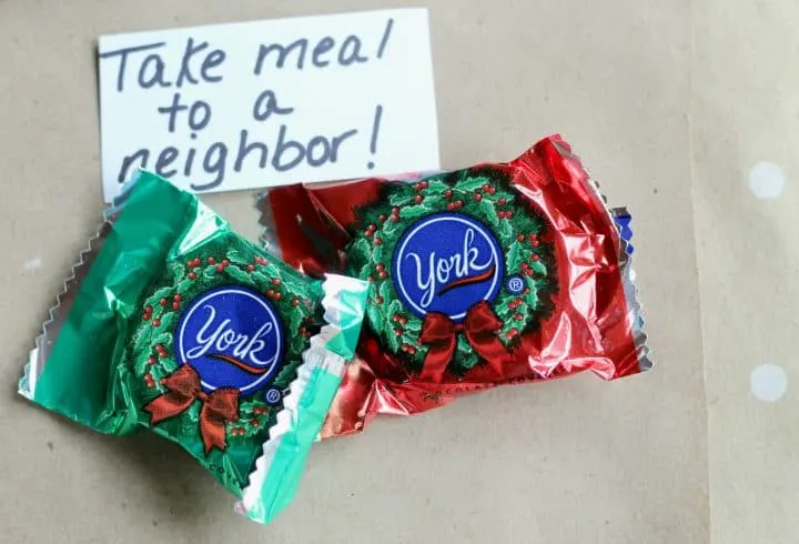 Two York peppermint patty candies and a handwritten instruction  to "Take a meal to a neighbor" as part of a random act of kindness advent calendar