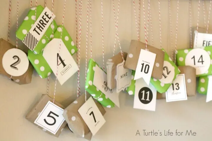 A DIY advent calendar made from kraft paper and scrapbook paper hanging on a wall from a pole