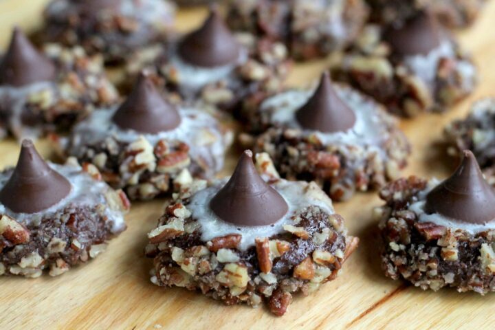 Chocolate Pecan cookies with Hershey Kisses sit on a wooden cutting board