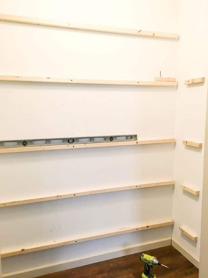Installing shelf supports as part of a DIY pantry project to create custom kitchen pantry shelves 