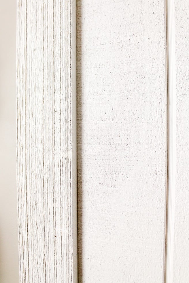 Painted rough sawn wood trim attached to a painted white shedding panel to make a DIY barn door. 