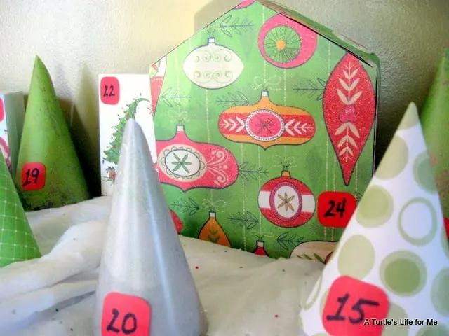 A homemade advent calendar made to look like a village  of houses and trees. 