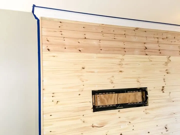 Painters tape outlines a DIY faux pallet TV wall before painting