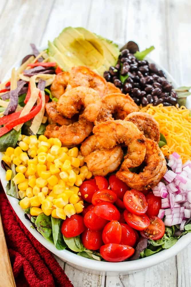 Easy Shrimp Taco Salad containing shrimp, corn, avocado, tomatoes, onions, beans and tortilla chip strips