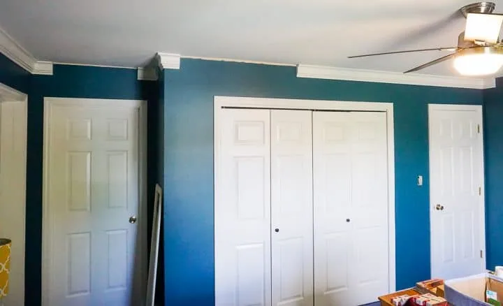 teal walls with crown molding being installed in some spots