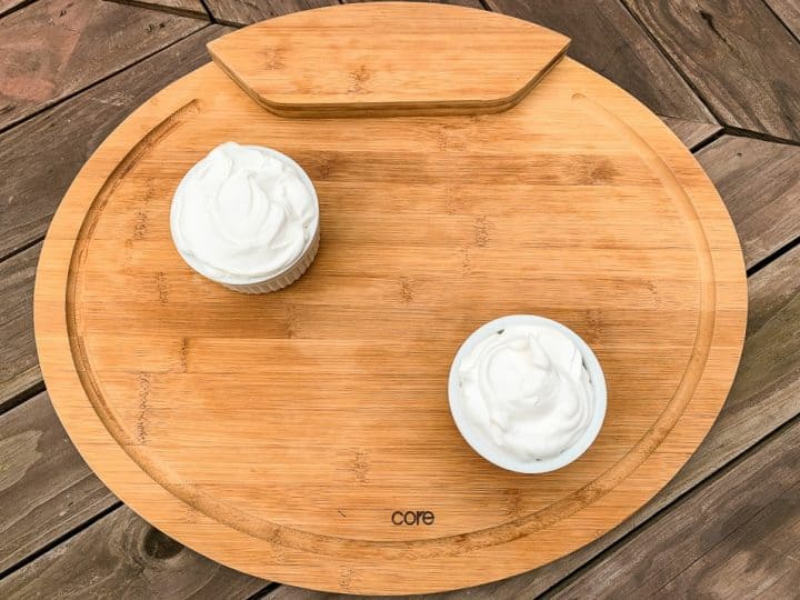 cutting board with 2 small cups of whipped cream