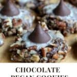 A pinterest pin with an image of a batch of chocolate pecan cookies. The Text says Chocolate Pecan Cookies with a Kiss