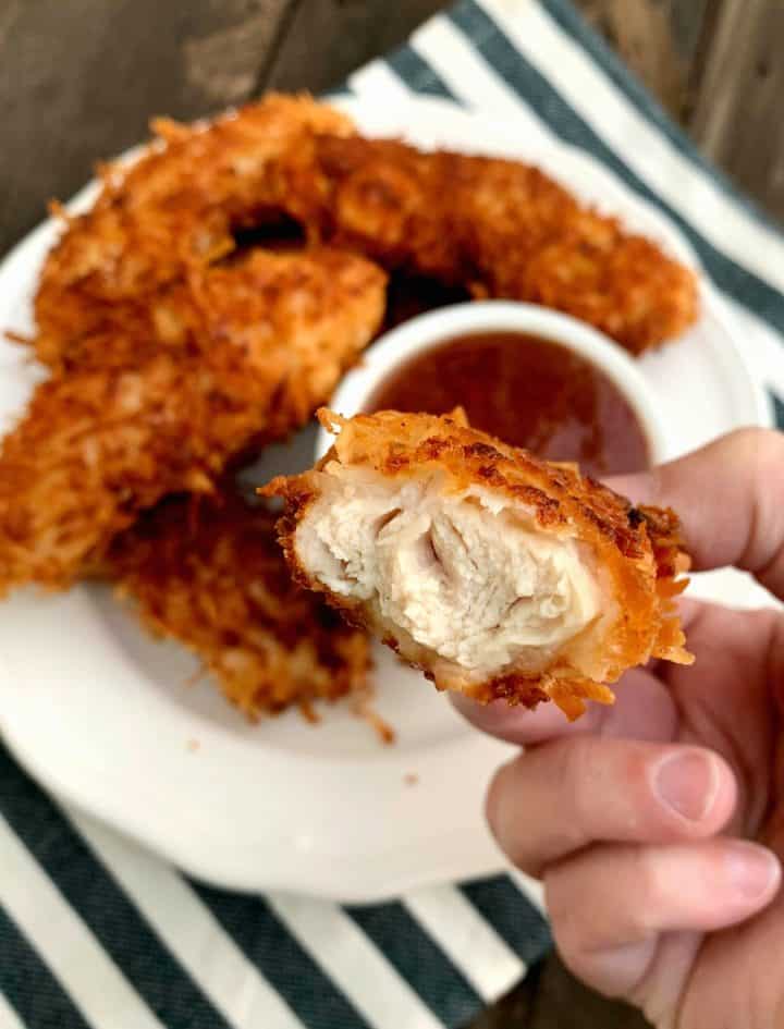 a coconut chicken tender with a bite taken out of it