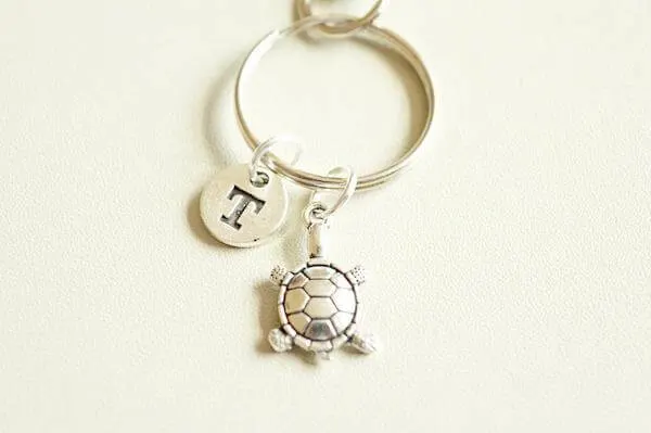 A small silver turtle keyring with an initial F