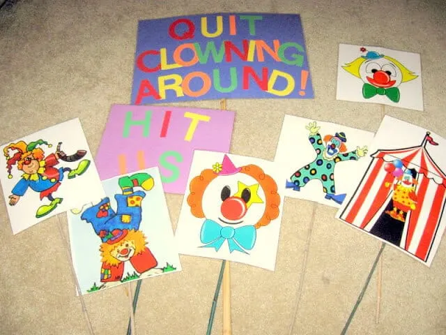 Clown images are colored, laminated, and attached to garden stakes as part of an outdoor end of year school party game.