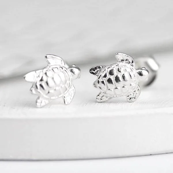 Sterling silver turtle stud earrings on  a white marble background