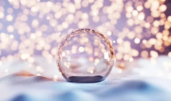 An empty glass Christmas ball ornament on snow with bokeh white background