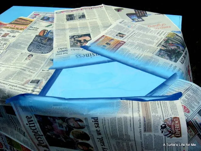 Newspaper covers part of a desktop in preparation for spray painting a stencil on the desk