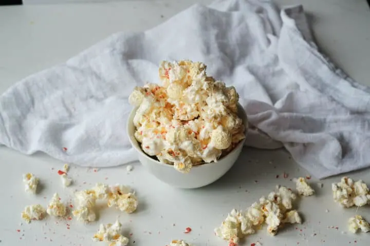 peppermint white chocolate popcorn with crushed candy canes in a bowl