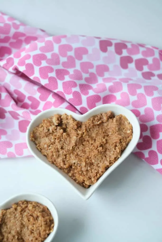 Chocolate oatmeal in a heart shaped bowl for Valentine's Day breakfast, with a heart pattern napkin in the shot