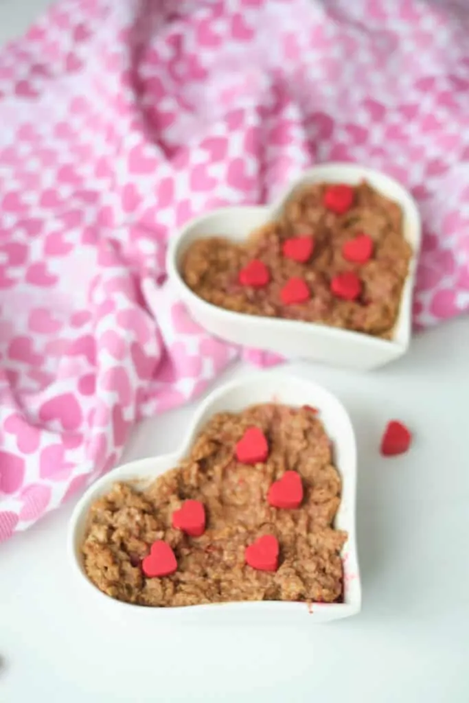 Chocolate oatmeal served in a heart shaped bowl and garnished with red hearts made from melting wafers