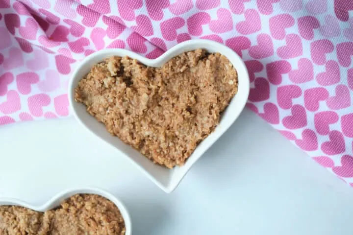 Chocolate oatmeal in a heart shaped bowl for Valentine's Day breakfast, with a heart pattern napkin in the shot