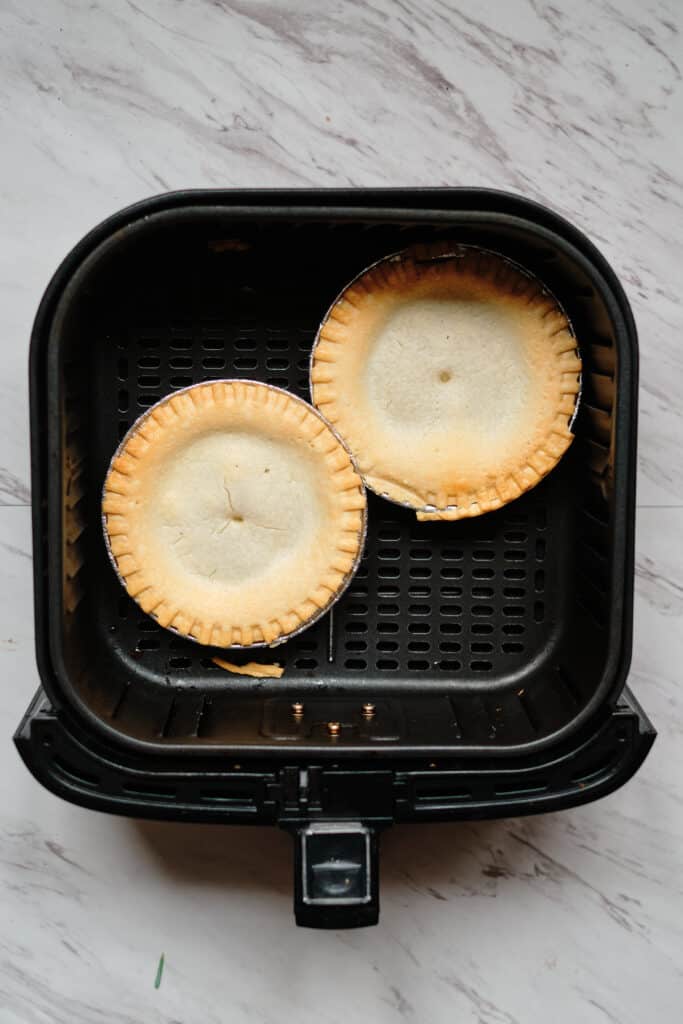 Two small frozen pot pies in an air fryer after cooking
