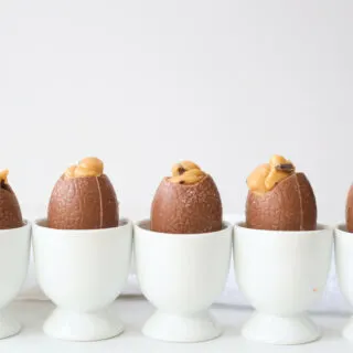 A row of peanut butter filled easter eggs in which egg cups against a white background