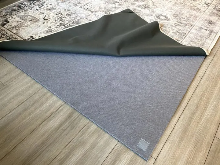 The Ruggable Kamran Hazel rug is pulled back from a thick underpad to show the Ruggable washable layer system as part of a Ruggable review blog post