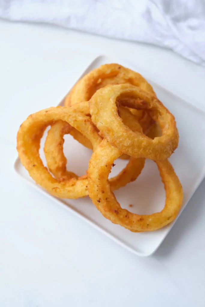 Frozen onion rings after being cooked in an air fryer on a dinner plate